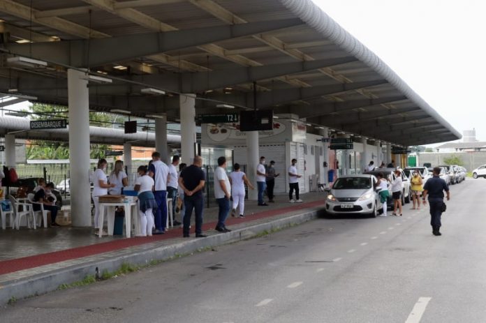 estação palhoça, onde é feita a vacinação por drive-thru; profissionais de saúde na plataforma; fila de carros; policial na pista