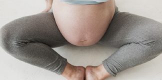 A foto mostra a barriga de uma grávida com calça legging cinza e pernas abertas enquanto os pés se tocam. As doulas de Santa Catarina podem voltar a auxiliar nos partos de hospitais públicos depois de um anos do serviço interrompido.