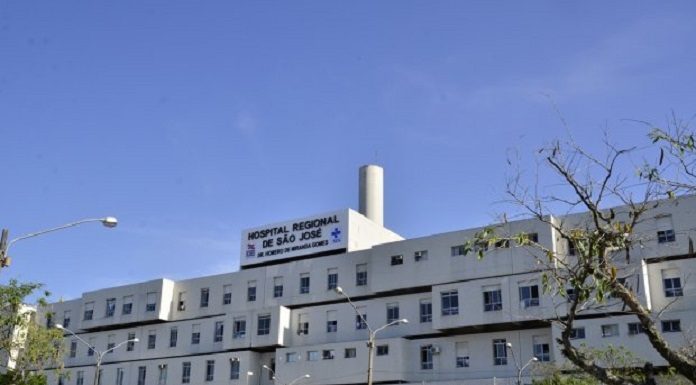 Visão lateral diagonal do Hospital Regional de São José, que registrou ontem o segundo apagão em março. A estrutura do hospital é grande, um prédio branco e em cima se lê a identificação. O céu está azul e há algumas árvores em volta.