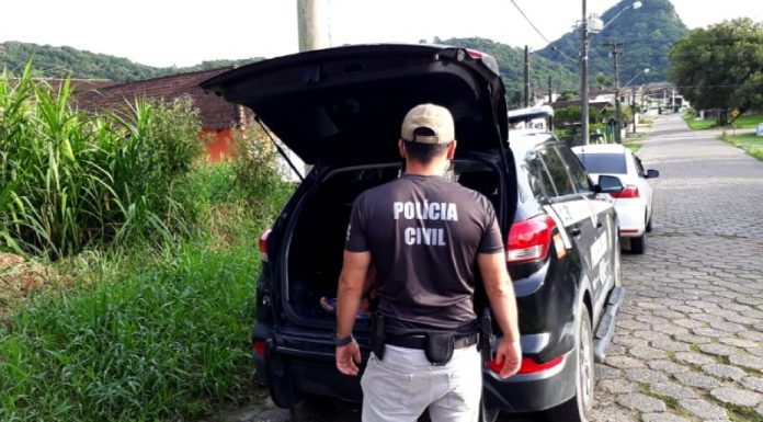 policial civil atrás de uma caminhonete da pc com porta-malas aberto estacionada em rua de paralelepípedo na deflagração da operação rescaldo