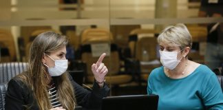 deputadas paulinha e luciane carminatti, de máscara, sentadas lado a lado na bancada da alesc, com computadores a frente; paulinha aponta para algo