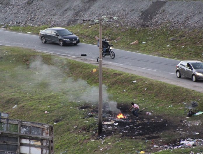 Morador de Campinas, em São José, registra próximo à via moradores em situação de rua em uma parte de grama com uma parte queimada, onde eles fazem fogo próximo a um poste. O aumento da população de rua está ligado ao furto de fiação elétrica nas localidades, o material é revendido.