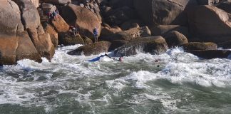 Na foto se vê o mar e ao fundo as pedras do costão com algumas pessoas nelas. Ontem, os bombeiros fizeram o resgate de seis pessoas que estavam no mar após a embarcação em que estavam colidir com o costão.