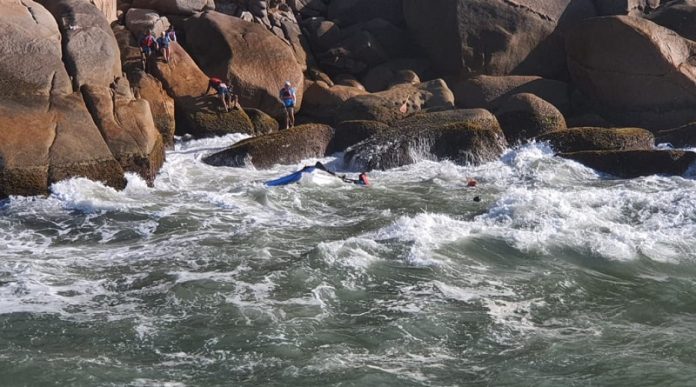 Na foto se vê o mar e ao fundo as pedras do costão com algumas pessoas nelas. Ontem, os bombeiros fizeram o resgate de seis pessoas que estavam no mar após a embarcação em que estavam colidir com o costão.