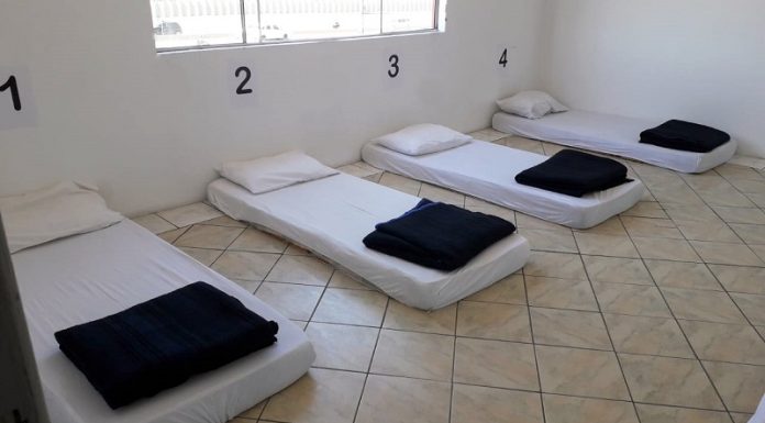 Em um quarto branco com janela, quatro colchões estão encostados na parece com numerações acima, a roupa de cama é branca e o cobertor dobrado é escuro. O abrigo emergencial de São José foi montado para atender as pessoas durante as noites de frio intenso.