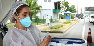 profissional de saúde usando máscara e epi maneja doses de vacina em drive-thru - vacinção de 60 anos na grande florianópolis