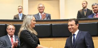 Em foto de arquivo, Daniela de roupa preta e cabelos loiros aperta a mão de Carlos Moisés, de terno escuro. Em volta é possível ver cinco homens de terno. O governador e a vice foram convocados para depor na CPI da pandemia, do senado federal.