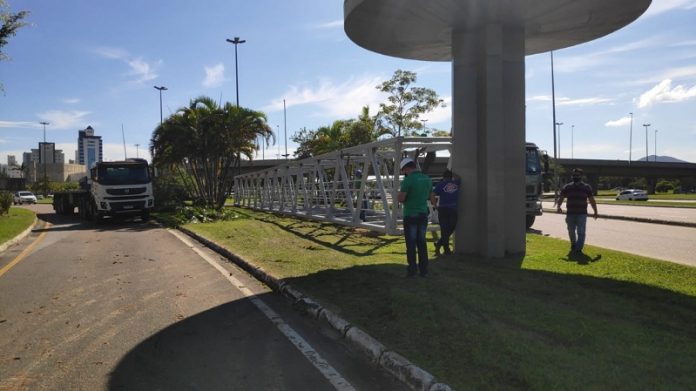 Parte da estrutura da passarela do CIC na grama, para ser recolocada.