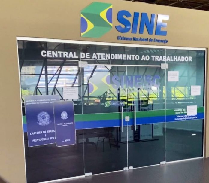 Porta de vidro do Sine, sinalziado em azul, um adesivo de uma carteira de trabalho na porta