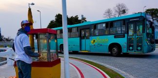 ônibus de transporte intermuicipal da empresa estrela saindo sda ponte herc´pilio luz e na calçada em primeiro plano pipoqueiro usando máscara com carrinho de pipoca