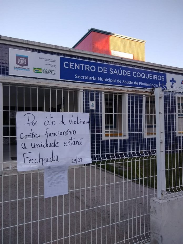 Foto da frente do centro de Saúde de Coqueiros, que tem um recado colado na grade de entrada, dizendo que por ato de violência a unidade estará fechado. Os profissionais relatam ameaças de pacientes aos funcionários do centro de saúde de coqueiros, em Florianópolis.