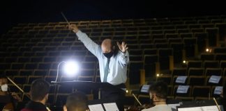 maestro rege orquestra sinfônica de santa catarina e ao fundo auditório vazio