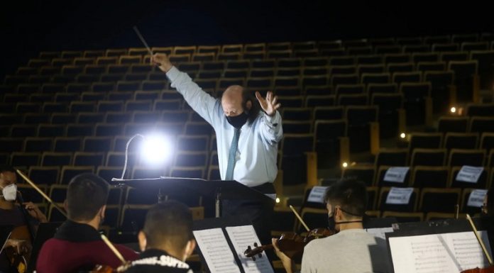 maestro rege orquestra sinfônica de santa catarina e ao fundo auditório vazio