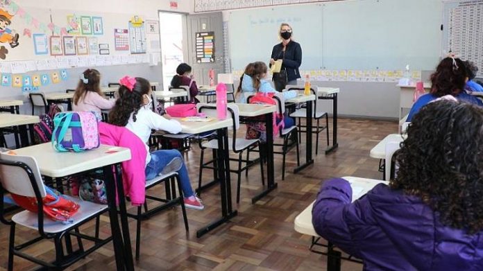 professora em sala de auala com alunas sentadas - Aprovado aumento salarial para 49 mil profissionais da educação estadual