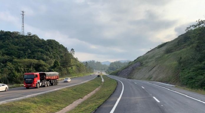 Trecho da BR-470 em SC, com uma pista cinza com marcas brancas à direita, uma parte com grama ao centro e à esquerda outra pista, com carros e um caminhão. O governador Carlos Moisés envia à Alesc o PL para doação de mais R$115 milhões para obras em rodovias federais.