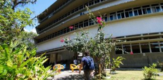 aluno anda por gramado com flores em volta e em frente a um prédio - calendário de retorno das aulas presenciais na udesc, ufsc e ifsc