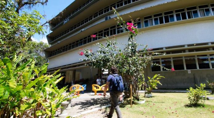 aluno anda por gramado com flores em volta e em frente a um prédio - calendário de retorno das aulas presenciais na udesc, ufsc e ifsc