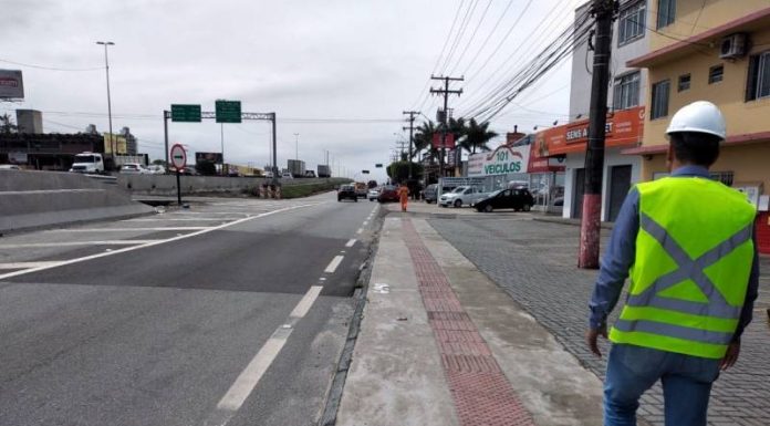 Acesso da BR-101 ao Kobrasol é interditado por duas semanas - trabalhador da concessionária com colete e capacete de EPI visto de costas na calçada ao lado da marginal da BR-101 em São José