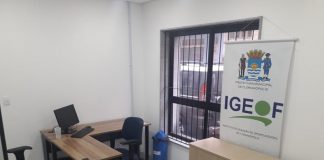 sala da nova sede do sine de florianópolis com mesa com computador alguns móveis e banner do igeof ao lado de janela