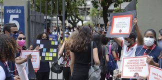 estudantes entrando em local de provam com pessoas no portão segurando cartazes e de máscara - Segundo dia do Enem tem provas de matemática e ciência da natureza