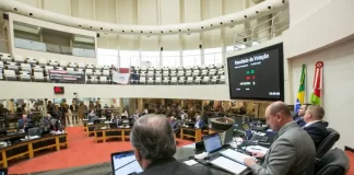 deputados na mesa da presidência da alesc com bancadas e demais parlamentares em baixo ao fundo