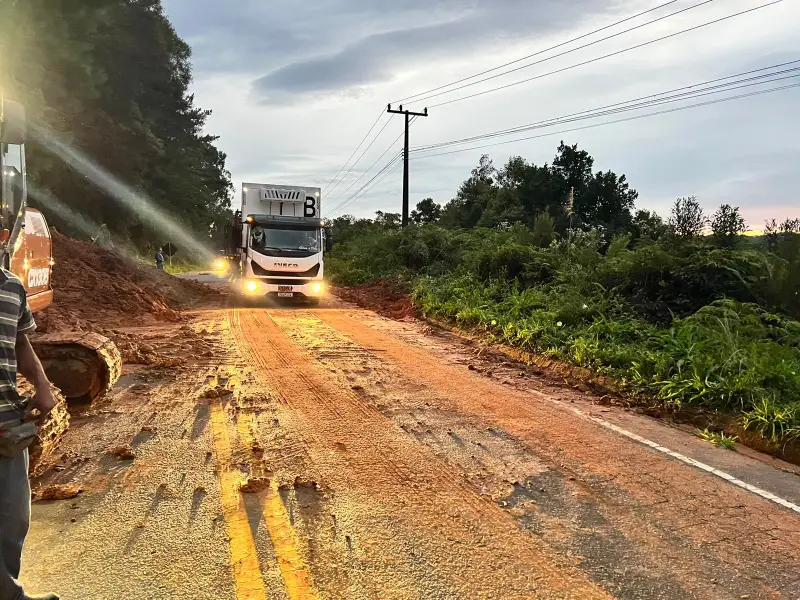 caminhão passando por parte da pista da sc-108 ao lado de queda de barreira